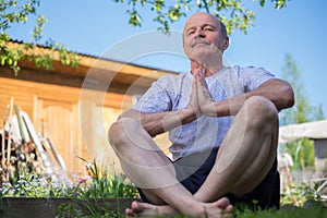 Yoga at park. Senior man with mustache with namaste sitting.Concept of calm and meditation.