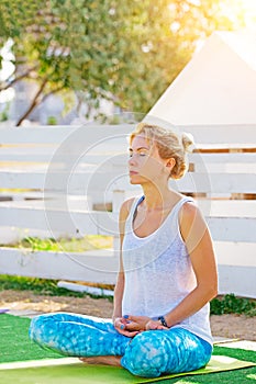 Yoga in the park, young woman doing exercises with group of mixed age people