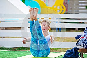 Yoga in the park, young woman doing exercises with group of mixed age people