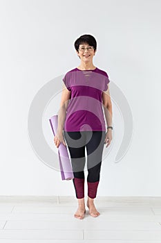 Yoga, people concept - Portrait of a middle age woman after yoga with her mat