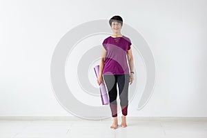 Yoga, people concept - Portrait of a middle age woman after yoga with her mat on white background with copy space