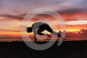 Yoga Poses. Woman Practicing Cat Stretch Asana On Ocean Beach. Female Silhouette Standing In Marjariasana Pose At Beautiful Sunset