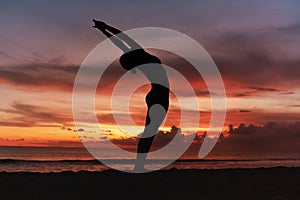 Yoga Poses. Woman Standing In Backbend Asana On Ocean Beach. Female Silhouette Practicing In Anuvittasana Pose.