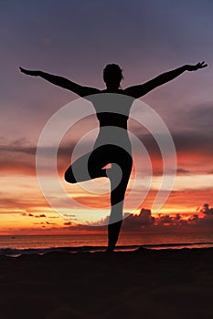 Yoga Poses. Woman Standing In Tree Pose Balancing Asana On Ocean Beach. Female Silhouette Practicing Vrikshasana.