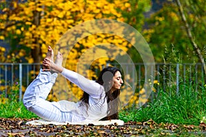 Yoga position by a young woman in the park in autumn photo