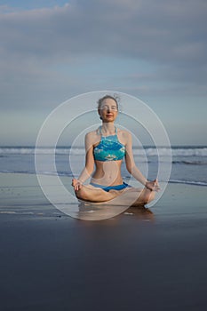 Yoga practice on the beach. Lotus pose. Padmasana. Hands in gyan mudra. Closed eyes. Meditation and concentration. Zen life.