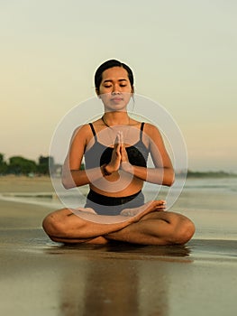 Yoga practice on the beach. Lotus pose. Padmasana. Hands in namaste mudra. Closed eyes. Meditation and concentration. Relaxation