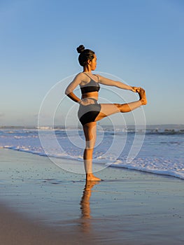 Yoga practice on the beach. Utthita Hasta Padangusthasana, Extended Hand-to-Big-Toe Pose. Standing balancing asana. Fit body.