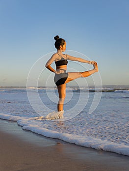 Yoga practice on the beach. Utthita Hasta Padangusthasana, Extended Hand-to-Big-Toe Pose. Standing balancing asana. Fit body.