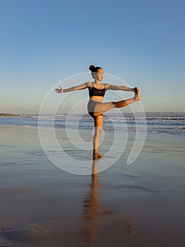 Yoga practice on the beach. Utthita Hasta Padangusthasana, Extended Hand-to-Big-Toe Pose. Standing balancing asana. Fit body.