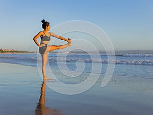 Yoga practice on the beach. Utthita Hasta Padangusthasana, Extended Hand-to-Big-Toe Pose. Standing balancing asana. Fit body.