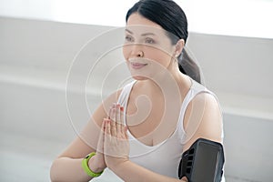 Brunette female performing namaste, pressing hands together, wearing pulsometer photo