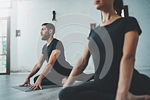 Yoga Practice Exercise Class Concept. Two beautiful people doing exercises.Young woman and man practicing yoga indoors.