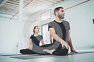 Yoga Practice Exercise Class Concept. Two beautiful people doing exercises.Young woman and man practicing yoga indoors.