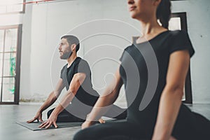 Yoga Practice Exercise Class Concept. Two beautiful people doing exercises.Young woman and man practicing yoga indoors.