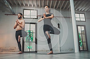 Yoga Practice Exercise Class Concept. Young woman and man practicing yoga indoors. Two sporty people doing exercises.