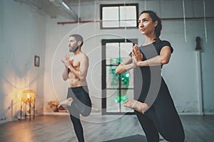 Yoga Practice Exercise Class Concept. Young woman and man practicing yoga indoors. Two sporty people doing exercises.