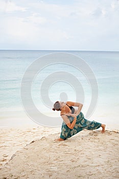 Yoga practice. Girl in variation of Warrior Virabhadra Yoga Pose at the sea beach