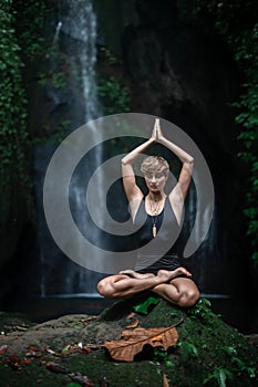 Yoga practice and meditation near waterfall. Woman practicing outdoor