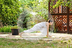Yoga Practice in the summer garden. Surya Namaskar - Salute to the Sun, Ashva sanchalanasana or rider`s pose