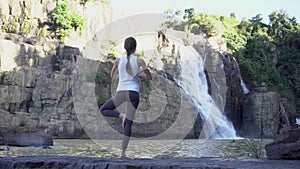 Yoga practice. Woman doing tree pose near waterfall in Dalat, Vietnam