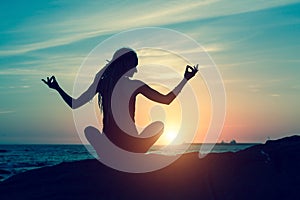 Yoga silhouette during amazing sunset. Meditation woman on the ocean.
