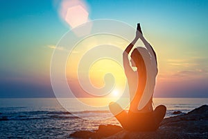 Yoga silhouette. Meditation fitness woman on the ocean during amazing sunset.