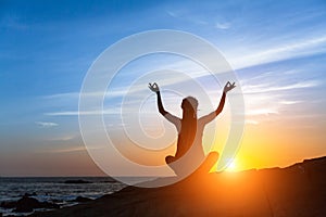 Yoga silhouette. Meditation fitness woman on the Sea beach during amazing sunset.