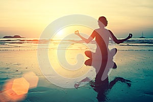 Yoga silhouette. Meditation girl on the sea during sunset.