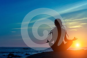 Yoga silhouette. Meditation woman on the ocean during amazing sunset.