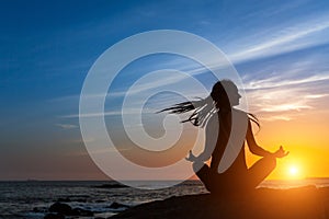 Yoga silhouette meditation woman on the Sea beach during amazing sunset.