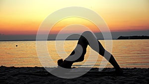 yoga silhouette. stretching outdoors. yoga beach. Woman silhouette is practicing yoga at the beach during sunset or