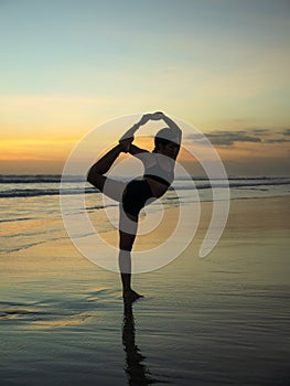 Yoga silhouette. Sunset beach yoga. Slim woman practicing standing asana Natarajasana, Lord of the Dance Pose. Balancing, back