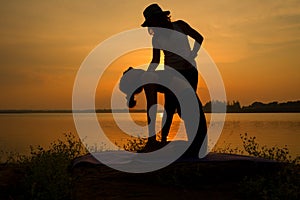 YOGA Silhouette Trainer and woman practicing yoga poses on sunset riverside of nature