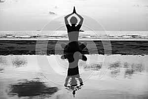 Yoga silhouette. Woman doing meditation near the ocean beach.