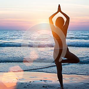 Yoga silhouette woman doing meditation near the ocean beach. Hobby.