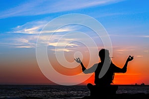 Yoga silhouette woman meditating in Lotus position on the ocean beach.
