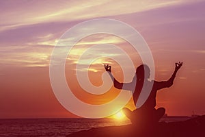 Yoga silhouette of woman meditating on the ocean.