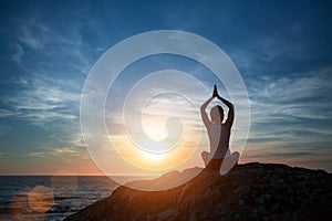 Yoga silhouette woman meditating on the ocean beach
