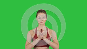 Yoga smiling woman with hands coupled on a green screen, chroma key.