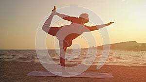 Yoga at sunset on the beach. woman doing yoga, performing asanas