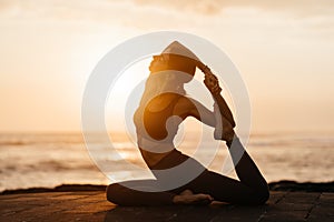 Yoga at sunset on the beach. woman performing asanas and enjoying life on the ocean