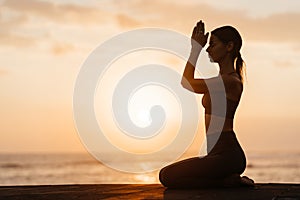 Yoga at sunset on the beach. woman performing asanas and enjoying life on the ocean