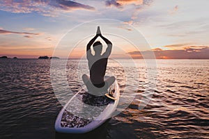 Yoga on SUP, silhouette of man sitting in lotus position on stand up paddle board