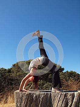 Yoga Superstar lady does a backbend on tree stump