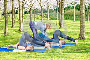 Yoga teacher helping the group with Halasana