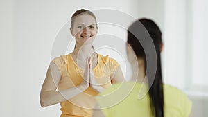 Yoga teacher is helping woman to do the asana