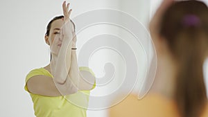 Yoga teacher is helping woman to do the asana