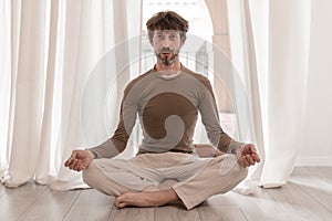 Yoga teacher sitting in the lotus position with their eyes closed.