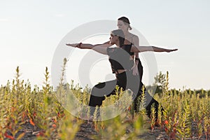 yoga teacher and student practicing warrior pose outdoors